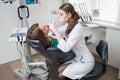 Female dentist with dental tools - mirror and probe treating patient teeth at dental clinic office Royalty Free Stock Photo