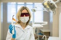 Female dentist doctor with safety glasses shows a Dental curing light in dental office.