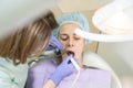 Female dentist doctor treats teeth of a young girl