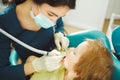 Female dentist drilling teeth the little boy. Young patient at a doctor`s appointment. Royalty Free Stock Photo