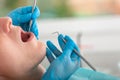 A female dentist examines the oral cavity of the patient with a tool with a mirror. Close-up portrait of a patient with Royalty Free Stock Photo