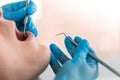 A female dentist examines the oral cavity of the patient with a tool with a mirror. Close-up portrait of a patient with Royalty Free Stock Photo