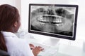 Female dentist examining jaw xray on computer in clinic