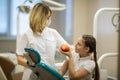 Female dentist gives apple for teenage girl in dental clinic