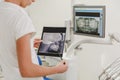 A female dentist holds a photo of a human skull in the dental office