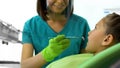 Female dentist looking at little girl teeth, routine dental checkup in clinic Royalty Free Stock Photo