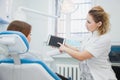 Female dentist and patient discussing treatments in a tablet application. Royalty Free Stock Photo