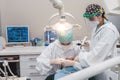 Female dentist with a patient in her office. Patient with open mouth and woman dentist working. dental health concept