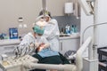 Female dentist with a patient in her office. Patient with open mouth and woman dentist working. dental health concept