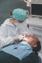 Female dentist with a patient in her office. Patient with open mouth and woman dentist working. dental health concept