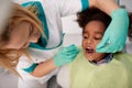 Female dentist repair tooth to black child