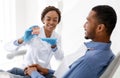 Female dentist showing male patient plastic model of human jaw