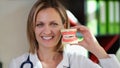 Female dentist smiling and shows artificial jaws in her hand closeup.