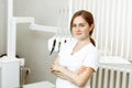 Female dentist standing with his hands crossed and looking at camera. Young female dentist in white coat at workplace.