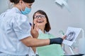 Female dentist talking to woman patient, discussing x-rays of teeth and jaws