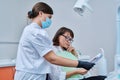 Female dentist talking to woman patient, discussing x-rays of teeth and jaws