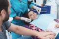 A female dentist is treating a girl. She is sitting on the dental chair. She is afraid and her father holds her hand. Royalty Free Stock Photo