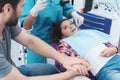 A female dentist is treating a girl. She is sitting on the dental chair. She is afraid and her father holds her hand. Royalty Free Stock Photo