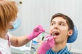 Female dentist is treating a patient tooth in dental office wit