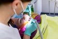 Female dentist treating teeth to patient, young woman in chair at dental clinic Royalty Free Stock Photo