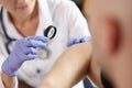 Female dermatologist examining patient skin with magnifying glass at consultation in hospital. Royalty Free Stock Photo