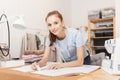 Female designer dressmaker working on sewing machine in studio