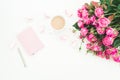 Female desk with pink roses bouquet, diary, coffee mug and marshmallows on white background. Flat lay. Top view