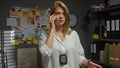 A female detective in an office analyzes evidence while speaking on the phone, badge visible Royalty Free Stock Photo