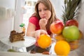 Female on diet in dilemma whether to eat chocolate cake or orange from fridge