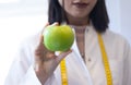 Female dietitian in apron and tape measure holding apple Royalty Free Stock Photo