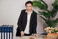 the female director in the office stands at the desk with the book in the office