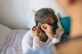 Female doctor applying hearing aid to senior man ear