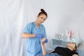 A female doctor beautician makes a procedure shugaring on the fingers of the right hand woman to the patient