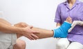 Female doctor in a blue medical gown checking broken leg on male patient Royalty Free Stock Photo