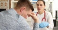 Female doctor calms an upset male patient at clinic appointment