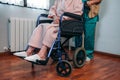 Doctor carrying elderly patient in a wheelchair Royalty Free Stock Photo