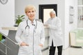 Female doctor in coat keeping hands in pockets. Royalty Free Stock Photo