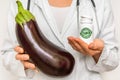 Female doctor compare pile of pills with fresh eggplant