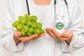 Female doctor compare pile of pills with fresh grapes