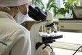 A female doctor conducts medical research using a microscope. Royalty Free Stock Photo