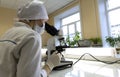 A female doctor conducts medical research using a microscope. Royalty Free Stock Photo