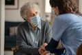 Female doctor consoling senior woman wearing face mask during home visit Royalty Free Stock Photo
