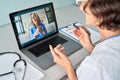 Female doctor consulting older senior patient during virtual video call visit.