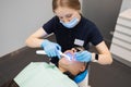 Female doctor dentist uses ultraviolet lamp while filling the male patient`s teeth.