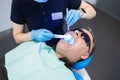 Female doctor dentist uses ultraviolet lamp while filling the male patient`s teeth.