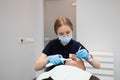 Female doctor dentist uses ultraviolet lamp while filling the male patient`s teeth.