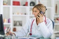Female doctor at desk talking on phone Royalty Free Stock Photo