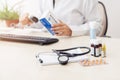 Female doctor entering medication information into computer, there are various drugs on table