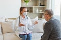 Female doctor examining older senior man in doctor office or at home. Old man patient and doctor have consultation in Royalty Free Stock Photo