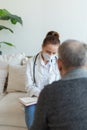 Female doctor examining older senior man in doctor office or at home. Old man patient and doctor have consultation in Royalty Free Stock Photo